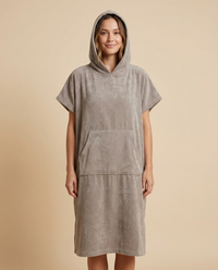 Woman wearing a hooded terry beach poncho in taupe
