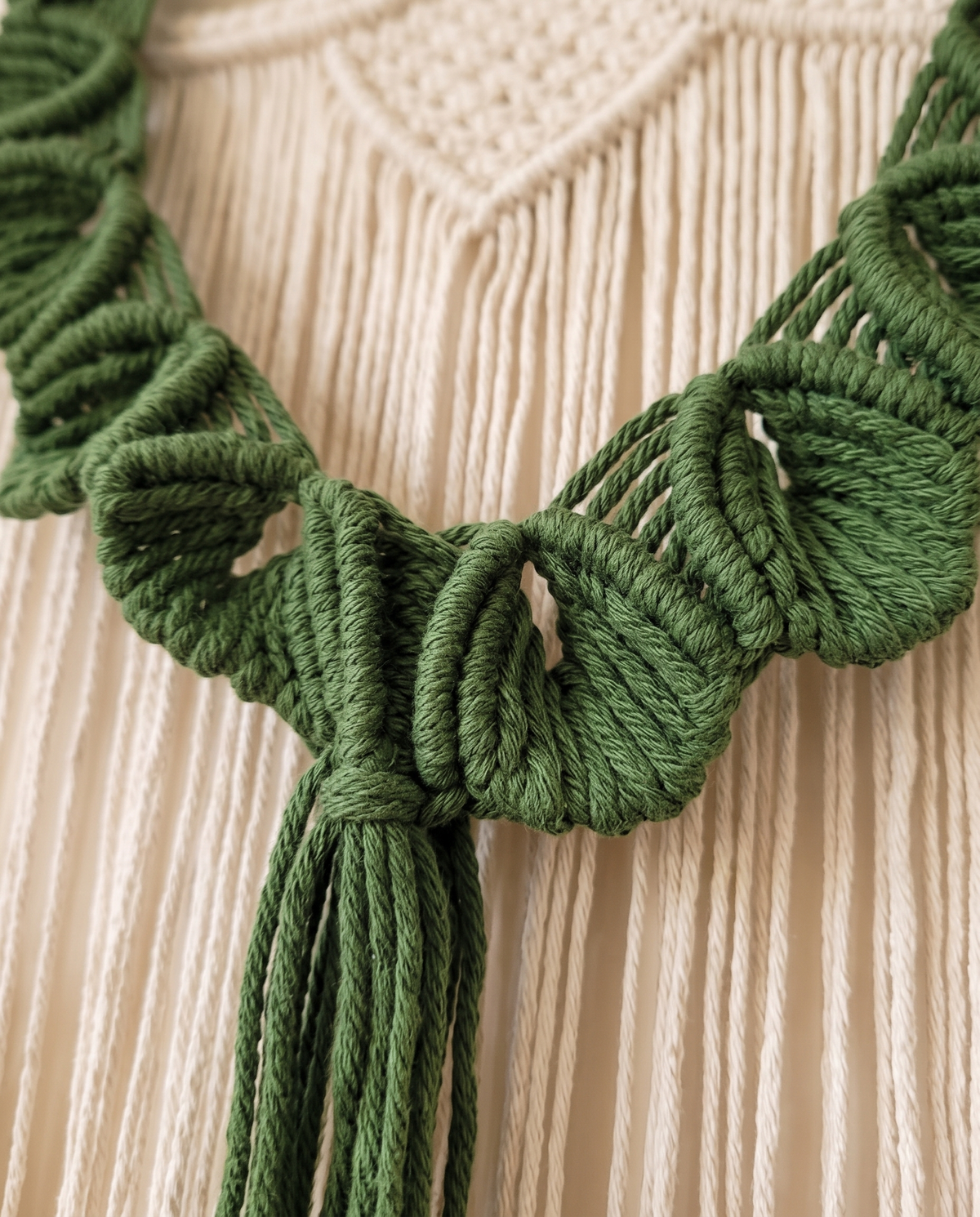 Close-up van handgeknoopte groene katoenen bladeren en kwast van het macramé wandkleed